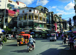 Home School Asia Busy street scene in Phnom Penh Cambodia with tuk tuks and motorbikes