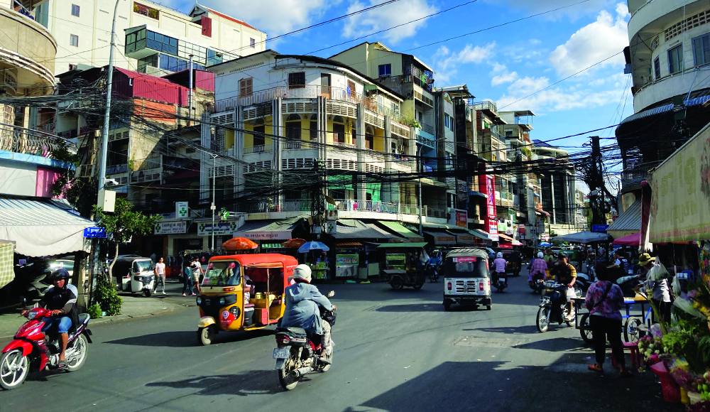 Busy street scene in Phnom Penh Cambodia with tuk tuks and motorbikes