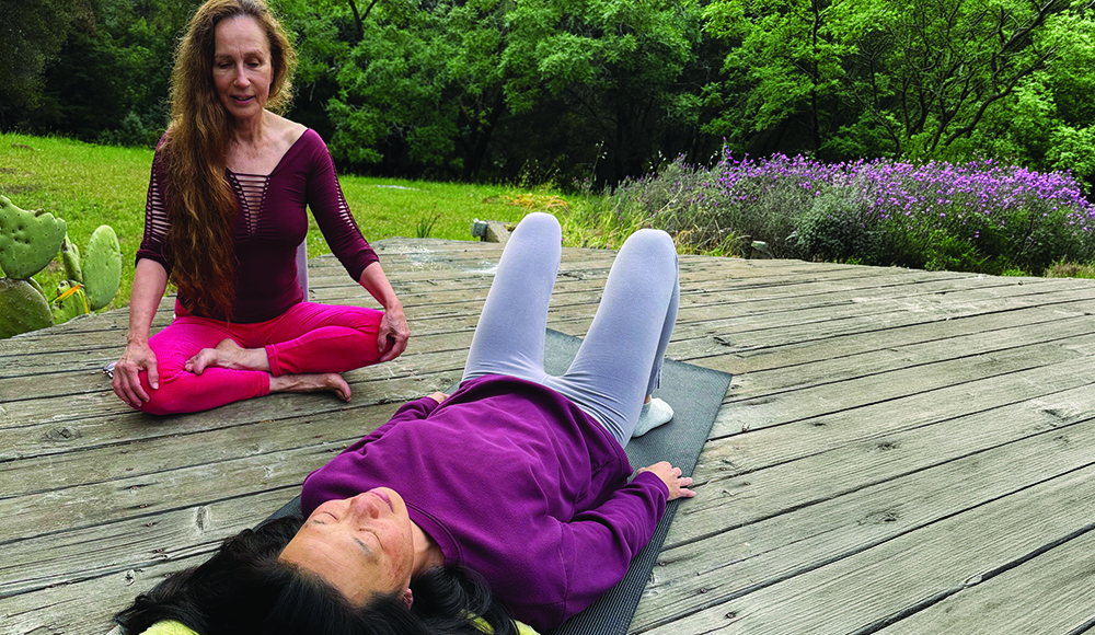 woman practicing guided relaxation on yoga mat with instructor outdoors Santa Cruz