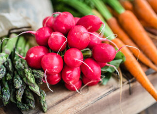 Happy Spring Foods Fresh spring vegetables including radishes, asparagus and carrots on a wooden surface