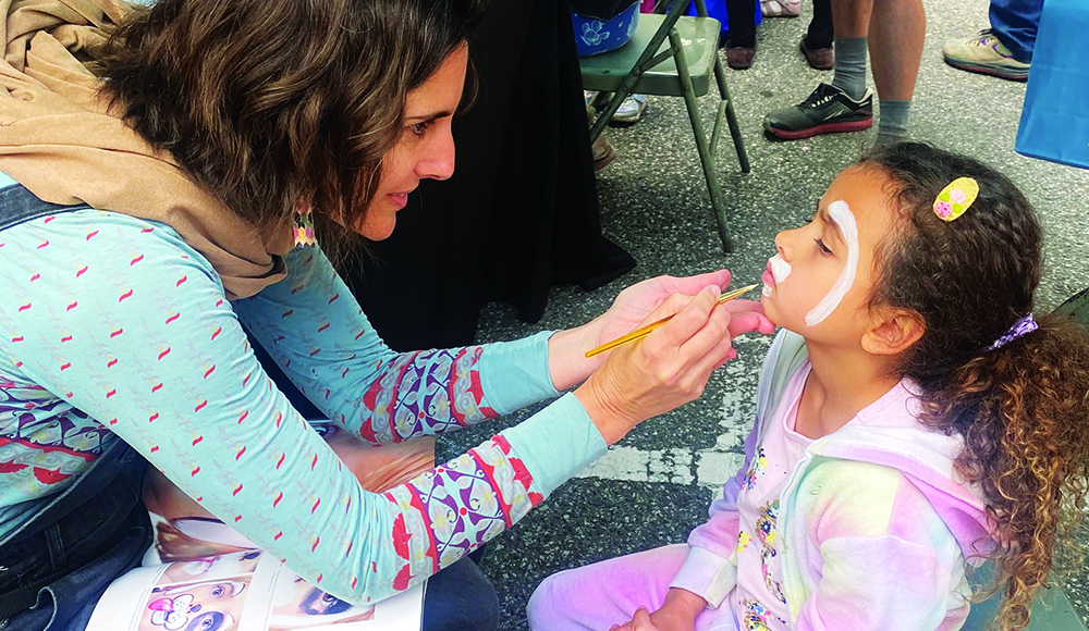 Child getting face paint at Santa Cruz Kids Day downtown
