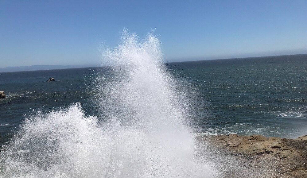 Large wave crashing violently against rocks at West Cliff Santa Cruz
