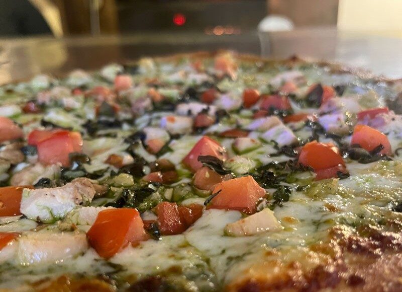 Creative pizza with herbs, tomatoes and melted cheese at Santa Cruz Pizza Week