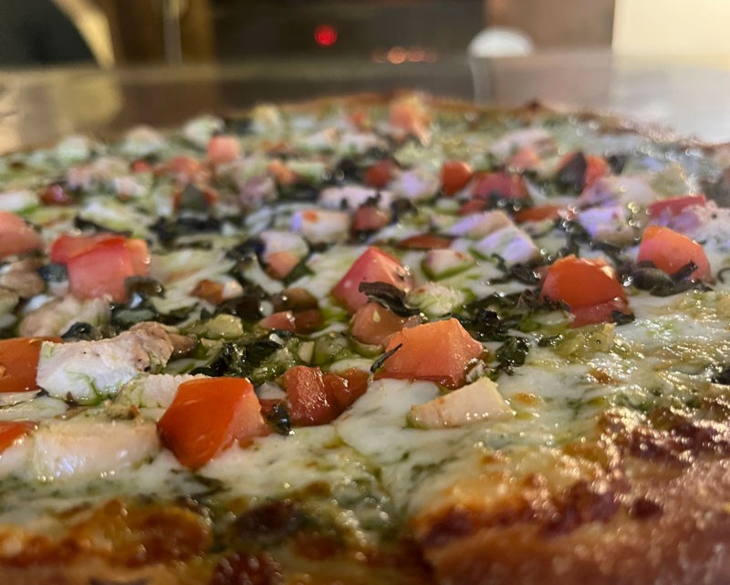 Creative pizza with herbs, tomatoes and melted cheese at Santa Cruz Pizza Week