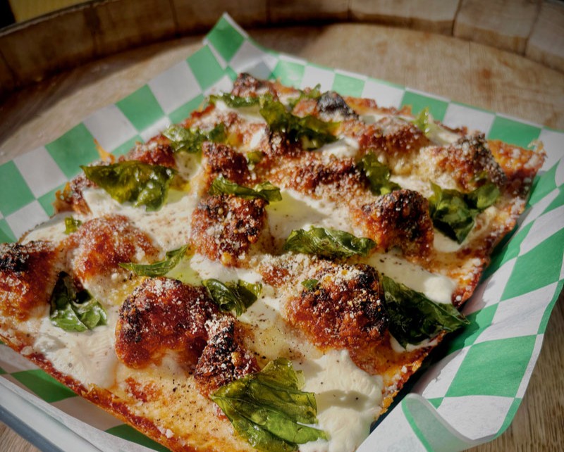 Sicilian-style square pizza with cheese, greens and crispy topping in Santa Cruz