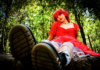 The Healing of Kat Moss Kat Moss of Scowl sitting in a red dress in a wooded setting