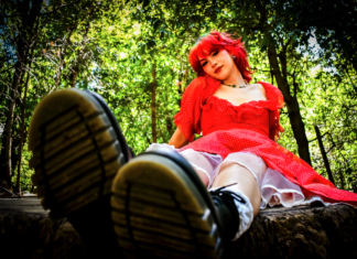The Healing of Kat Moss Kat Moss of Scowl sitting in a red dress in a wooded setting