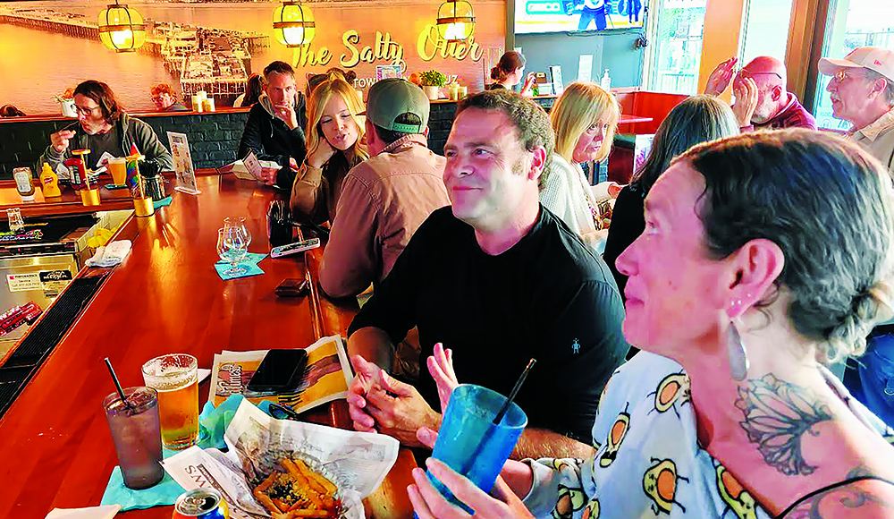 Patrons sit at the bar inside The Salty Otter in downtown Santa Cruz.