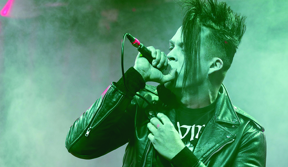 Dark Ride vocalist Emilio Menze sings into a microphone during a live performance.