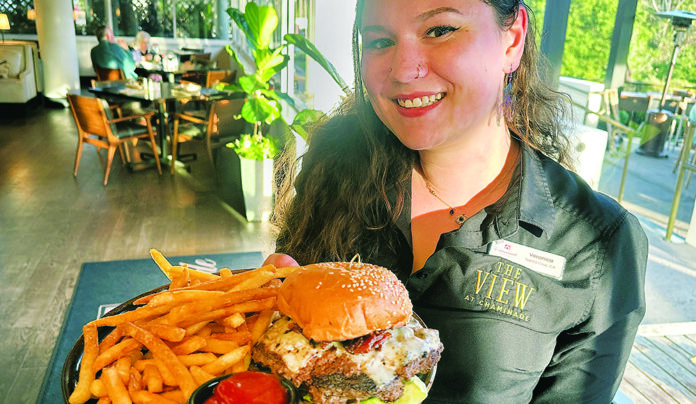 ย Hyper-Local Server Veronica Hodes holds The Bee Smash Burger with fries at The View at Chaminade.