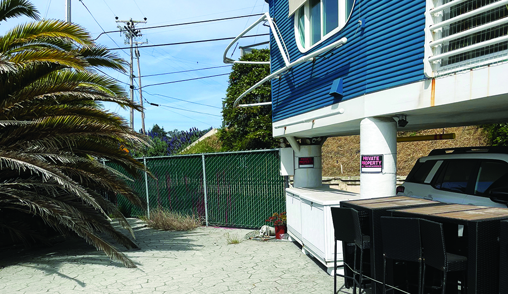 A green fence blocks a beachfront walkway beside homes in Rio del Mar.