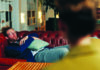 Below the Surface A person reclines on a red couch during a therapy session, with the therapist blurred in the foreground.