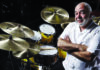 Things to do in Santa Cruz Drummer Peter Erskine sits beside a drum kit with cymbals.
