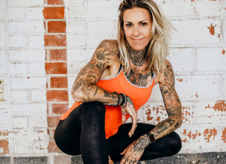 The Comeback Kid Fitness instructor Carina Reid poses against a white brick wall.