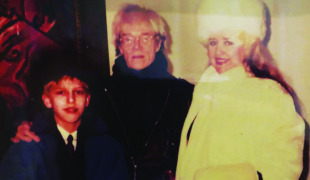 Young Jayce Bartok stands with Andy Warhol and LeAnn Bartok in a vintage family photo.