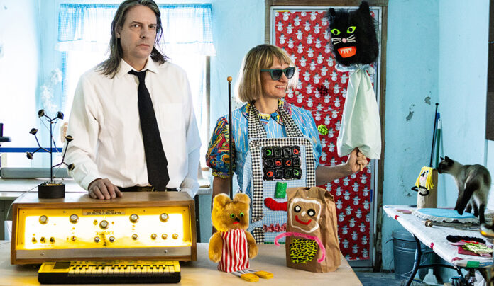 Things to do in Santa Cruz Quintron and Miss Pussycat pose with puppets and electronic instruments in a colorful room.