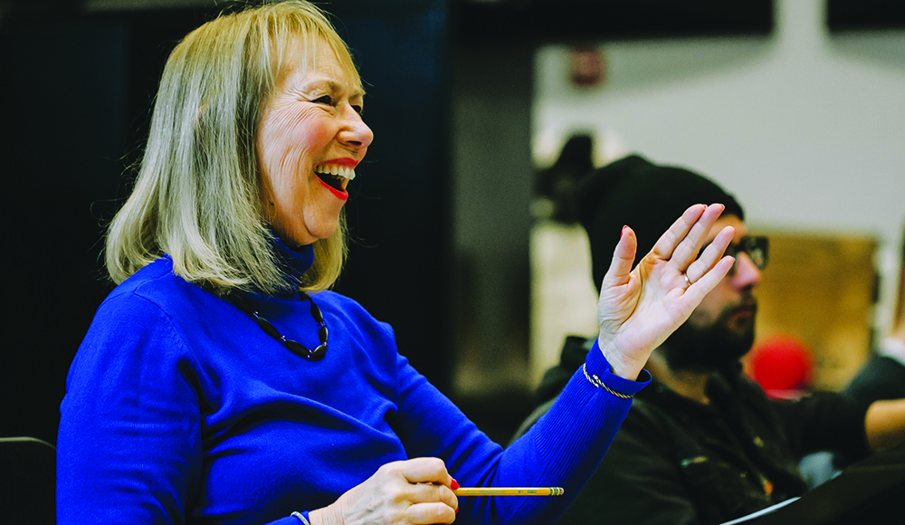Choral director Cheryl Anderson smiles and gestures during a rehearsal.