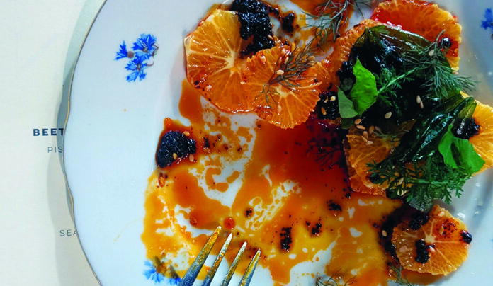 Flavor Savior A colorful citrus salad with herbs, sauce and charred accents is served on a plate at Bad Animal in Santa Cruz.