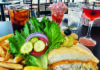 Family and Feast Crab melt sandwich, fries, shrimp cocktail and cocktails on a table overlooking Monterey Bay at Stagnaro Brothers Seafood Restaurant.