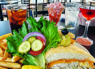 Family and Feast Crab melt sandwich, fries, shrimp cocktail and cocktails on a table overlooking Monterey Bay at Stagnaro Brothers Seafood Restaurant.