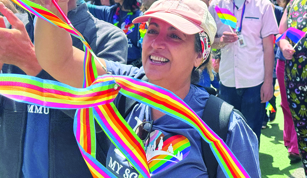 Person smiles while waving rainbow ribbons at the Santa Cruz Pride Parade.