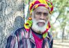 Things to do in Santa Cruz Israel Vibration reggae artist standing beside a tree in a colorful Rastafarian headwrap.