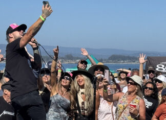 Things to do in Santa Cruz A singer performs in a crowd at an outdoor concert by the water as audience members raise their hands and take photos.