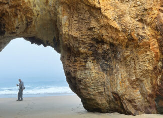 Don’t Be Blindsided A person stands beneath the Keyhole rock arch at Panther Beach near the ocean.
