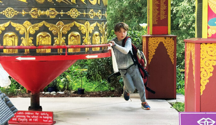 Rejoice, Rejoice A child spins a large prayer wheel at Land of Medicine Buddha in Soquel.