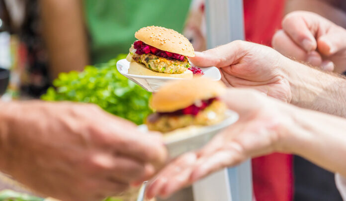 Green Beings: VegFest ’26 Hands hold small vegan sliders at Santa Cruz VegFest.