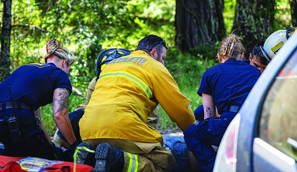 Firefighters and emergency medical responders assist a person beside a vehicle