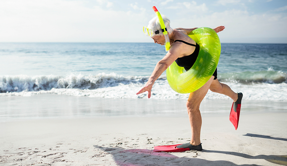 Older swimmer with snorkel and float preparing to enter the ocean