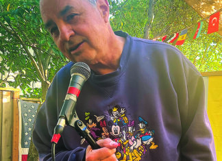 Emerging Talent Kevin Keelan speaking into a microphone at a Seabright garden performance space