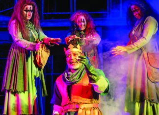 The three witches surround King Duncan in Santa Cruz Shakespeare’s Macbeth