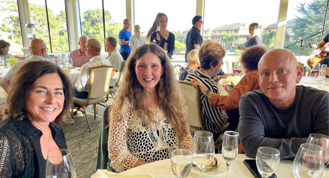 Three members of a Santa Cruz singles group smile for a photo while seated together at a restaurant table.