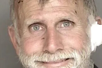 Violent Felon Runs Police booking photo of an older bearded man with white gauze near his right ear.