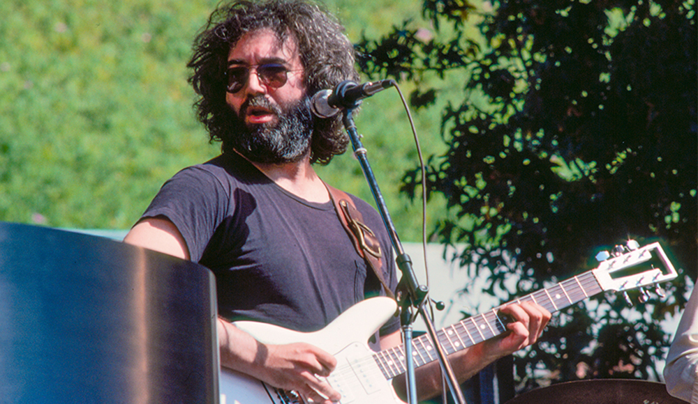 Jerry Garcia playing a white electric guitar outdoors in 1976