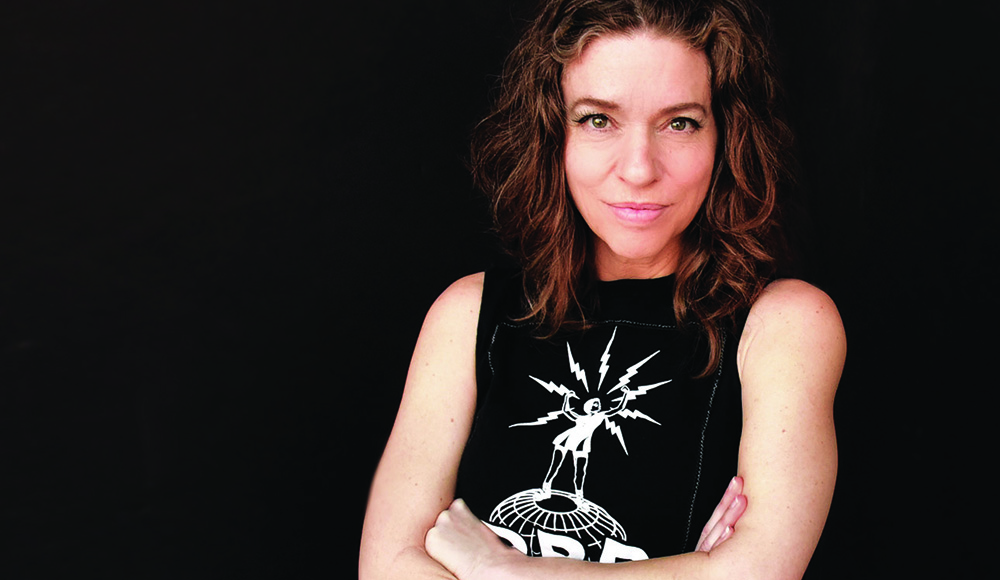 Portrait of singer-songwriter Ani DiFranco against a black background.