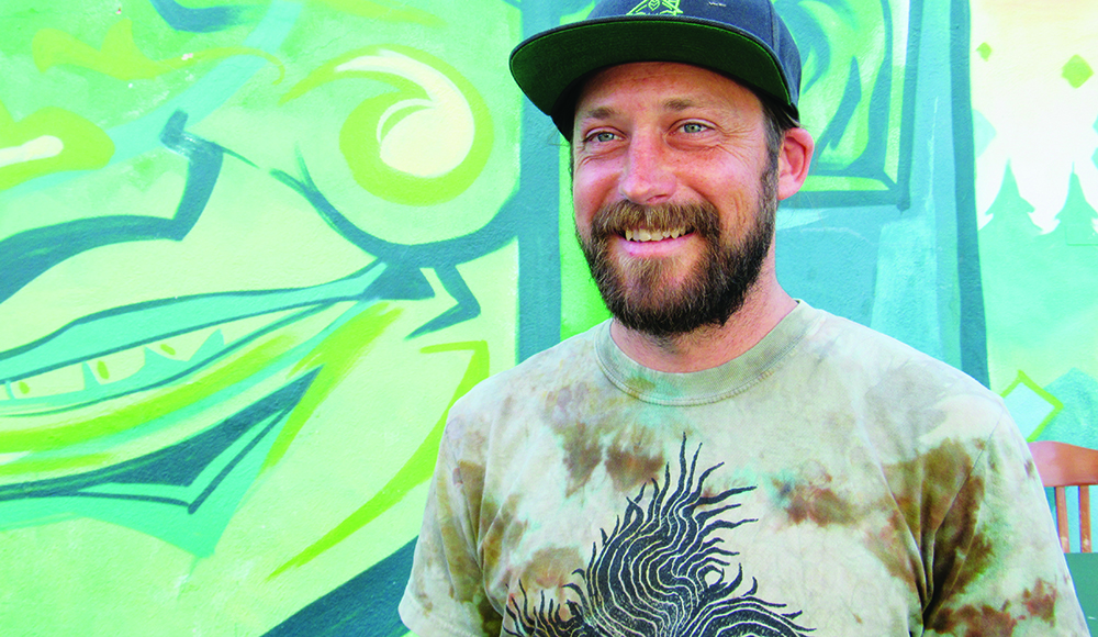 Shanty Shack co-owner Nathan Van Zandt standing in front of a colorful mural.