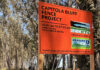 Fenced Out Orange Capitola Bluff Fence Project construction sign beside the coastal trail.