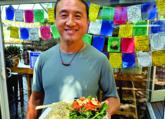 Peak Dumplings River Café owner Rabgee Kunchok holding beef momo dumplings and salad