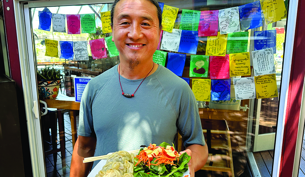River Café owner Rabgee Kunchok holding beef momo dumplings and salad