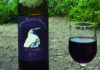 This Bird Flew Bottle of White Raven Winery 2016 Zinfandel beside a glass of red wine.