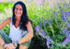 Flower Power Santa Cruz herbalist Julie Rothman seated beside blooming purple herbs.