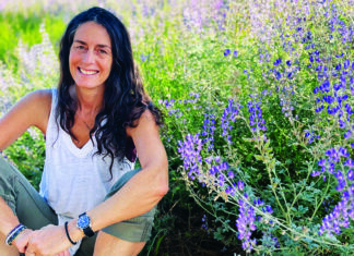 Flower Power Santa Cruz herbalist Julie Rothman seated beside blooming purple herbs.