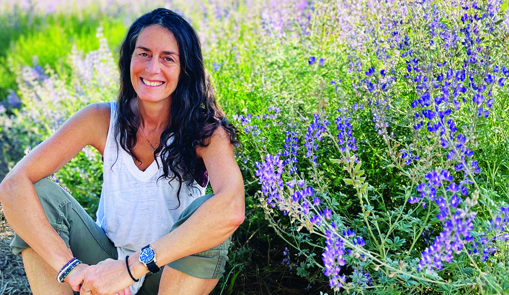 Santa Cruz herbalist Julie Rothman seated beside blooming purple herbs.