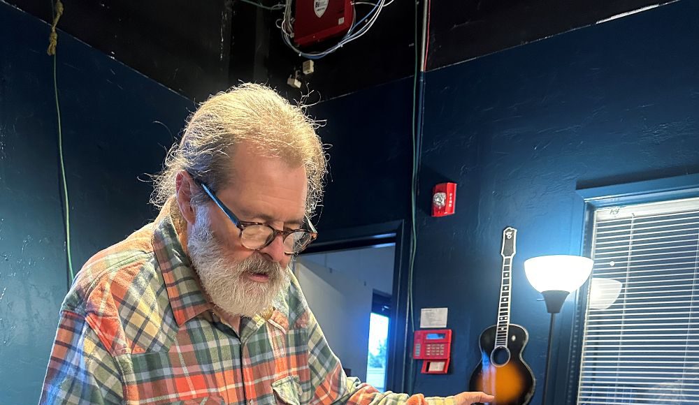 Santa Cruz Guitar Company founder Richard Hoover examines a handcrafted acoustic guitar.