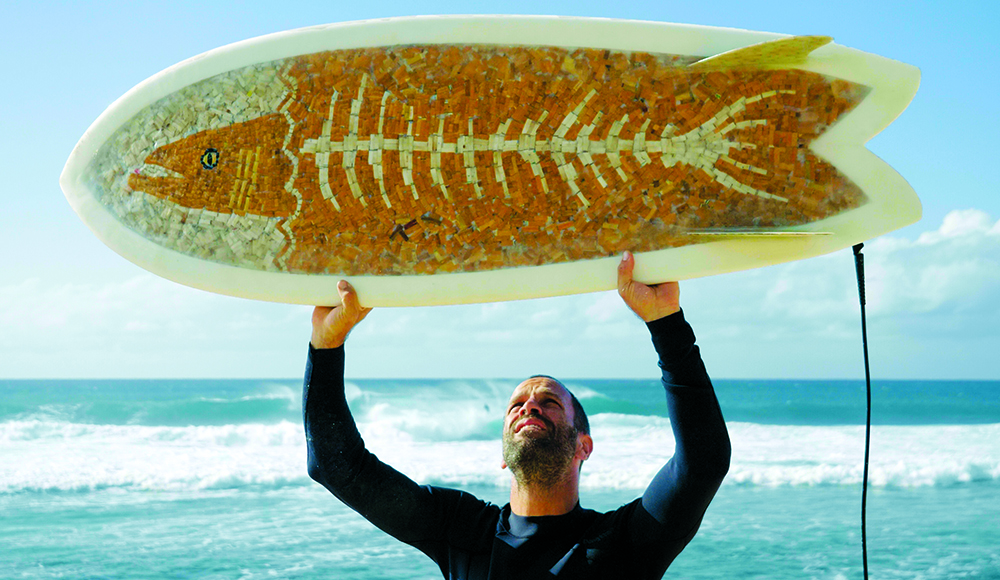 Jack Johnson holds one of Taylor Lane’s Ciggy Boards made with thousands of discarded cigarette butts in Hawaiʻi.