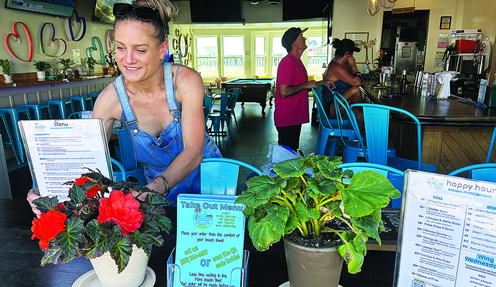 Bay Bar & Grill co-owner Brittny Beshore arranges plants and signs inside the Capitola Village bar and restaurant.