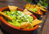 Oracles Unleashed Bowls of fresh guacamole topped with cheese and herbs and surrounded by tortilla chips.